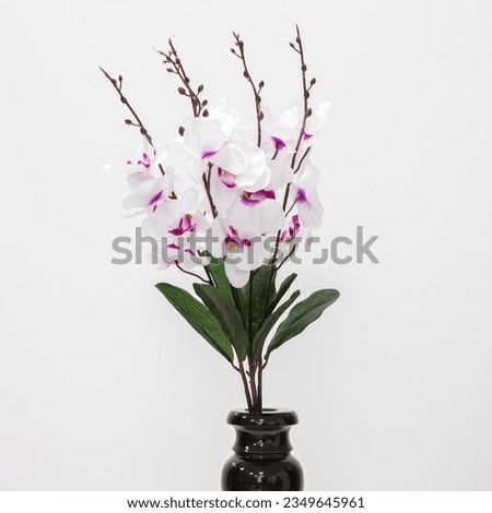 Artificial flowers in a black vase. Close up. On a white background.