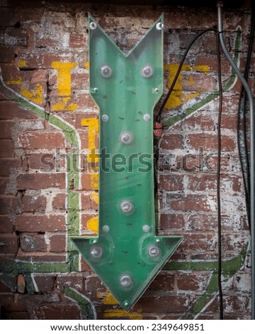 Green Arrow Pointing Down against painted brick wall