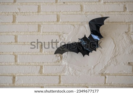 Black bat paper docorated on white brick wall. 2023 Halloween decoration concept.