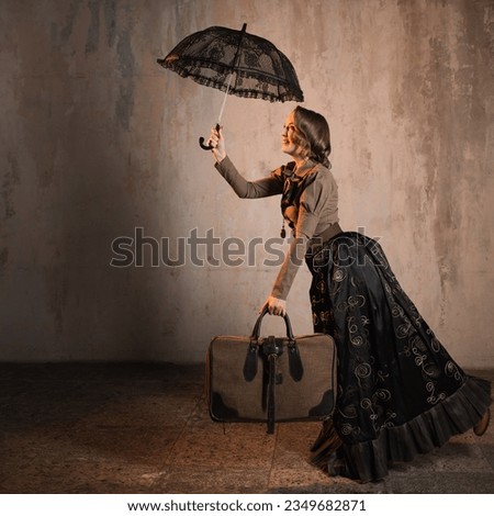 A stylish lady in an elegant Victorian-style suit, in a hat with an umbrella in her hands, is ready to take off like Mary Poppins Royalty-Free Stock Photo #2349682871