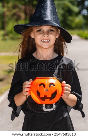 Child in a Halloween costume. trick or treat on the street. Little girl with pumpkin lantern and candy bucket. A child in a witch's hat. Autumn holidays are fun.