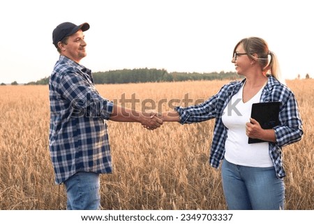 At the end of a grain purchase transaction, people shake hands while standing in a wheat field at sunset. Agriculture and small business. Two people are discussing the agricultural business. Royalty-Free Stock Photo #2349703337