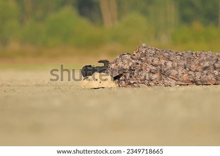 Photographer taking pictures of birds under camouflage.