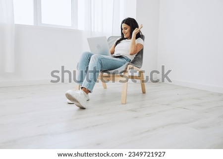 Woman relaxing at home sitting in a chair with her laptop and talking on video call with friends in covid-19, lifestyle home spirits. Mockup, free copy space