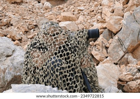 Photographer taking pictures of birds under camouflage.