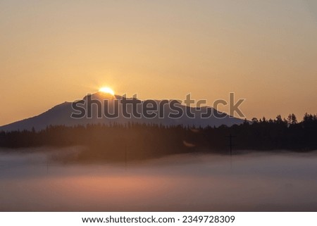 Fog over the fields, mountains in background on a summer morning in the Lowel River Valley outside Snohomish and Everett Washington