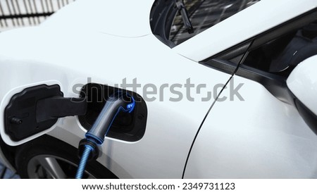 Electric car recharging with EV charger from charging station at public car park. Future innovative rechargeable EV car using alternative clean and sustainable energy. Peruse