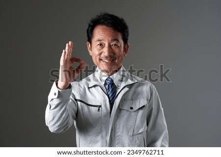 Asian middle aged worker OK gesture in black background