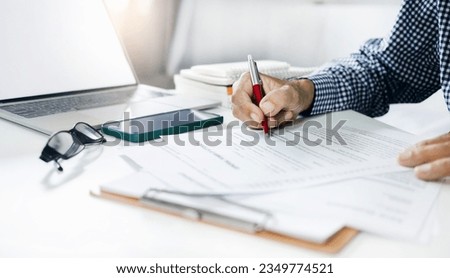 Asian businessman reviewing document reports at office workplace with computer laptop. legal expert, professional lawyer reading and checking financial documents or insurance contract before sign Royalty-Free Stock Photo #2349774521