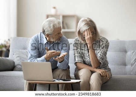 Frustrated elderly couple arguing about financial problems at laptop and calculator. Mad annoyed senior husband blaming mature upset wife on overspending, wrong payment, money crisis Royalty-Free Stock Photo #2349818683