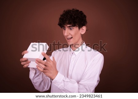 Funny young guy posing in the studio on a brown background. Holiday gifts.