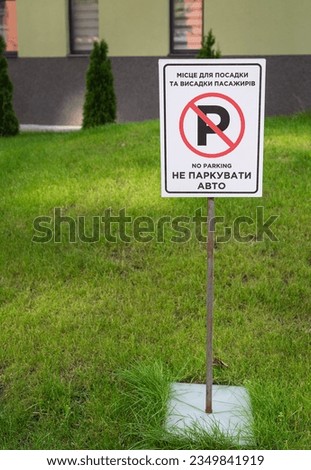 Road sign, No parking sign stands on a freshly mowed lawn. Selective focus, noise. Translation into Ukrainian