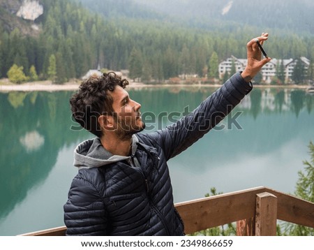 Photo of a man capturing the scenic beauty of a tranquil lake in the Italian Dolomites