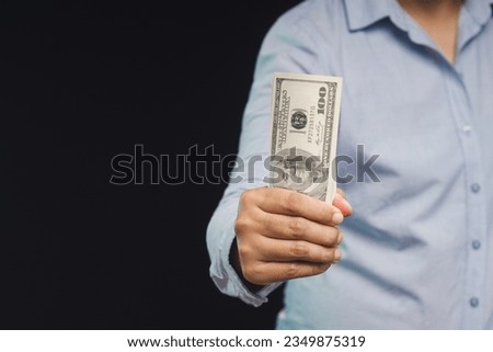 Money and Finance concept. Businesswoman holding US dollar bills while standing on a black background. Close-up photo