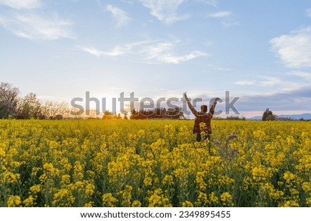 Boy walking in a field with flowers at sunset