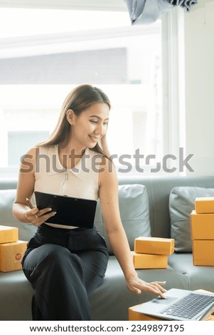 Asian businesswoman on sofa using laptop computer check customer's online delivery box order at home Starting SMEs, Small Business Entrepreneurs, Freelance Online Business Vertical picture