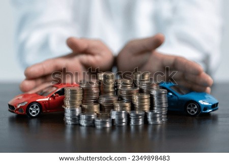Close-up Of A Person's Hand Protecting Increasing Stacked Coins And Blue Car. Saving money for car concept, trade car for cash concept, finance concept.
