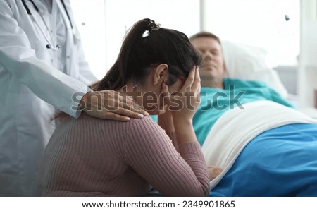 Woman in clinic crying near man in hospital bed Royalty-Free Stock Photo #2349901865