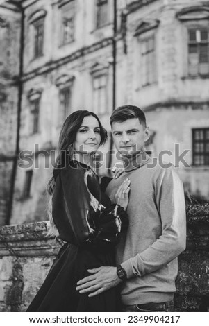 Bride hug groom. Female with male wall in street. Luxury couple near old Pidhirtsi Castle. Woman in long dress walks and man on stairs near ancient palace at sunset. Black and groom photo newlyweds.