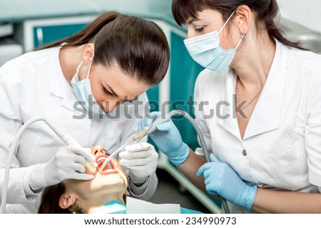 Dentist and nurse making professional teeth cleaning female young patient at the dental office Royalty-Free Stock Photo #234990973