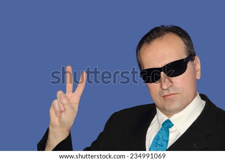 Man in black showing the victory sign on blue background.