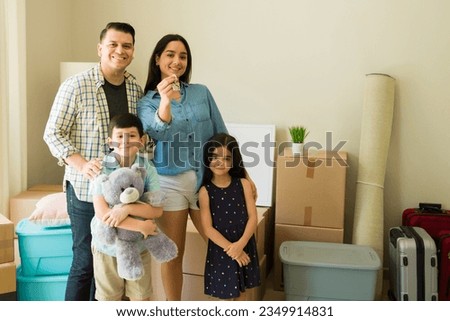 Portrait of a happy family with two kids smiling and unpacking boxes in their new home or apartment while relocating Royalty-Free Stock Photo #2349914831