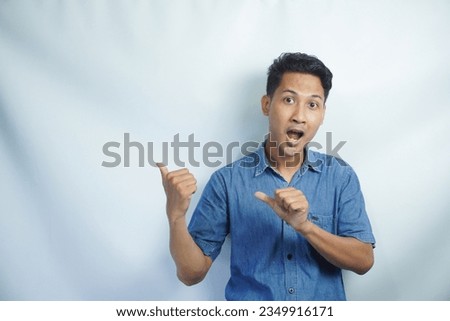 Omg, Cool Offer. Surprised young Asian man pointing at free space isolated over white studio background. Excited shocked man showing copy space and place for advert or promotional text, banner