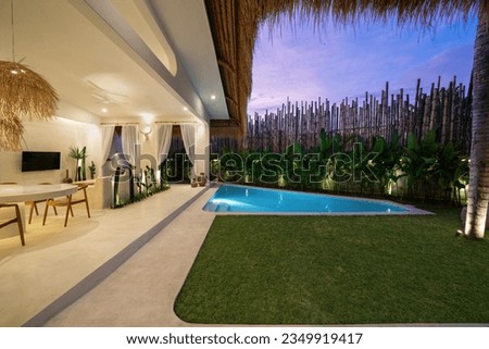 Tropical villa view with garden, swimming pool and open living room at sunset. Royalty-Free Stock Photo #2349919417