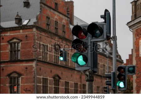 Selective focus at traffic green light and blur background of old classic european style brick building during raining day.