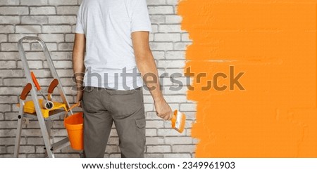 man renovating their house by painting the walls. banner with place for text.