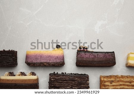 Flat lay composition with different tasty cakes on light grey marble table, space for text