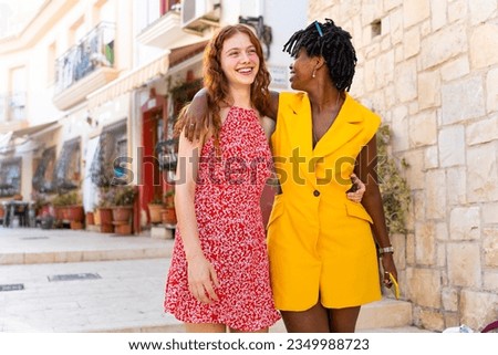 Two happy friends walk through the city with their arms around each other. Multiracial friendship concept. Royalty-Free Stock Photo #2349988723