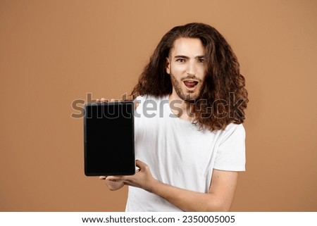 Great Application. Amazed Latin Guy Holding And Showing Digital Tablet With Empty Screen For Mockup, Recommending New App Or Online Website Posing Over Beige Studio Background