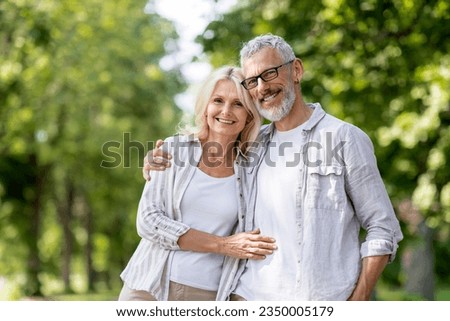Portrait Of Loving Senior Couple Embracing Outdoors And Smiling At Camera, Romantic Mature Spouses Hugging While Posing Together Outside, Older Man And Woman Bonding While Walking In Summer Park