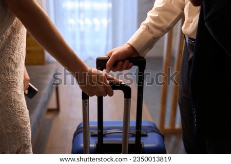 Close-up man and woman holding suitcases, entering or leaving hotel Royalty-Free Stock Photo #2350013819