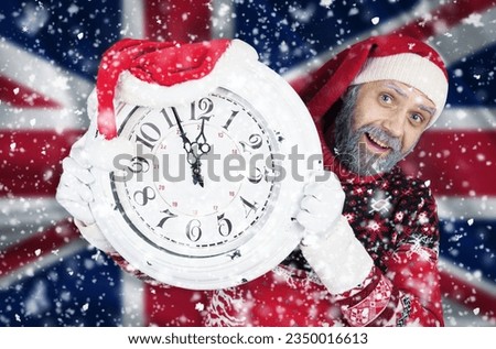 Santa Claus holds a clock in his hands, on which 5 minutes are left until the new year, Christmas, against the background of the flag of Great Britain. New year and christmas concept.