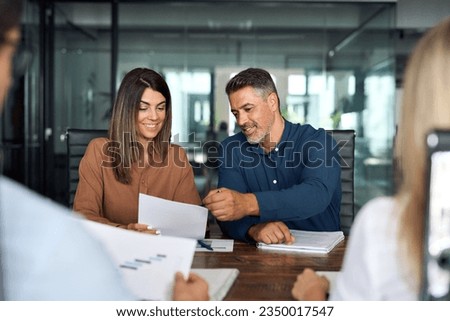 Professional executives business group working with documents at meeting in office. Smiling corporate board team having discussion planning company project strategy sitting at board room table. Royalty-Free Stock Photo #2350017547