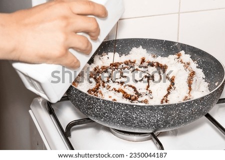 A picture of a chef cooking, A hand is pouring soy sauce on rice in a pan. Culinary experience at home. One person, horizontal image