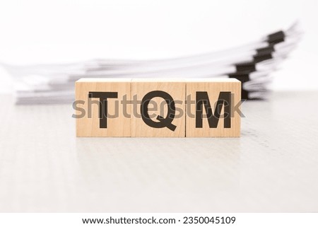 TQM letters on wooden cubes. the background is a white business papers. finance concept Royalty-Free Stock Photo #2350045109