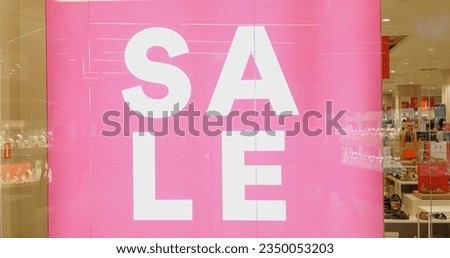 Pink color large bright advertisement banner of sale in display window of store. Big advertising display with promotion of retail discount selling.