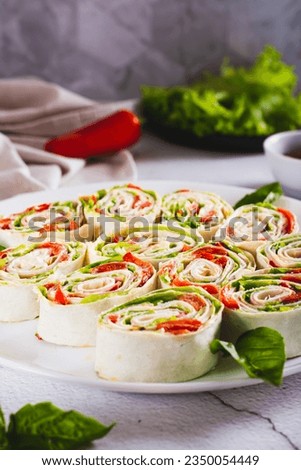 Italian rolled sandwiches with lettuce, ham and baked peppers in pita bread on a plate vertical view