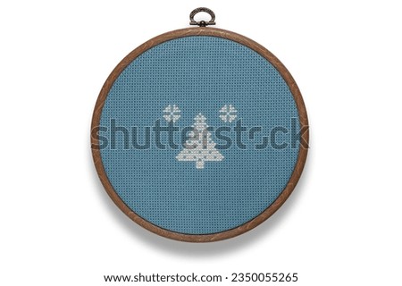 Cross-stitch ornament on blue canvas in round frame on white background. Save with adding the clipping path