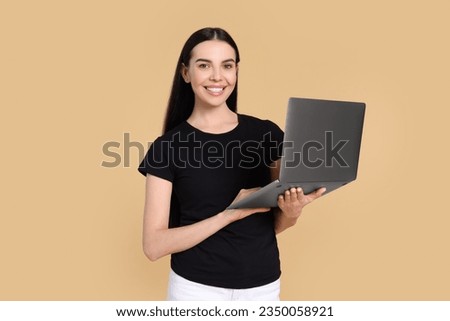 Happy woman with laptop on beige background