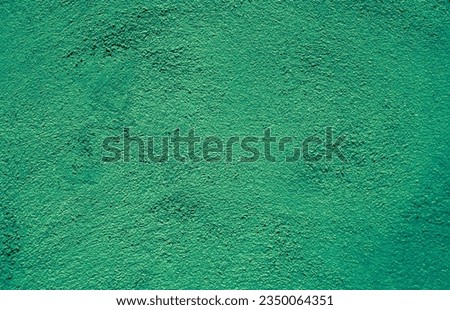 Abstract grunge green stucco wall background. Beautiful bright painted plaster texture. Rough textured wallpaper with copy space for design