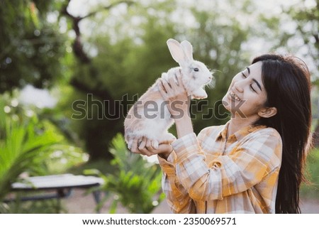 relationships of cheerful rabbit and happy young human girl, Asian woman holding and carrying cute rabbit with tenderness and love. Friendship with cute easter bunny. Happy of Easter's Day