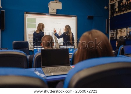 Female university student picked by the professor writing answers on smart board during classes at school. Royalty-Free Stock Photo #2350072921