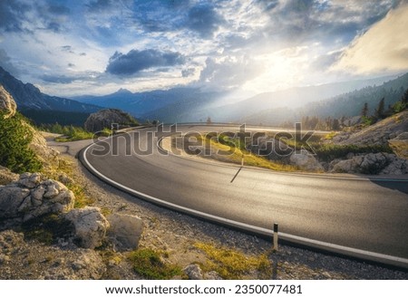 Mountain road at colorful sunset in summer. Dolomites, Italy. Beautiful curved roadway, rocks, stones, blue sky with clouds. Landscape with empty highway through the mountain pass in spring. Travel Royalty-Free Stock Photo #2350077481