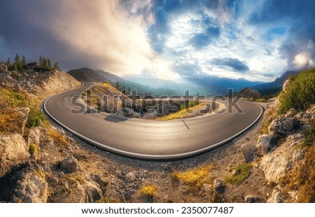 Mountain road at colorful sunset in summer. Dolomites, Italy. Beautiful curved roadway, rocks, stones, blue sky with clouds. Landscape with empty highway through the mountain pass in spring. Panorama Royalty-Free Stock Photo #2350077487