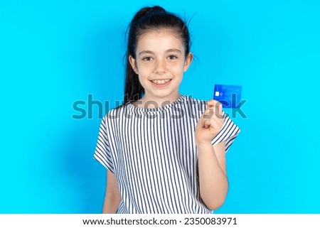 Photo of happy cheerful smiling positive caucasian kid girl wearing striped dress recommend credit card