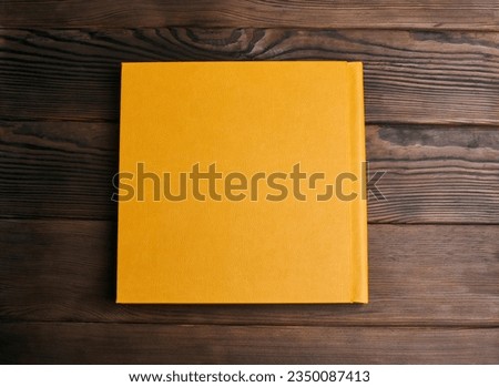 Stylish book with bright leather hardcover isolated on a wooden background. Back cover top view. Photo album, notebook, diary, planner or scrapbook. Template for photographers or designers. Royalty-Free Stock Photo #2350087413